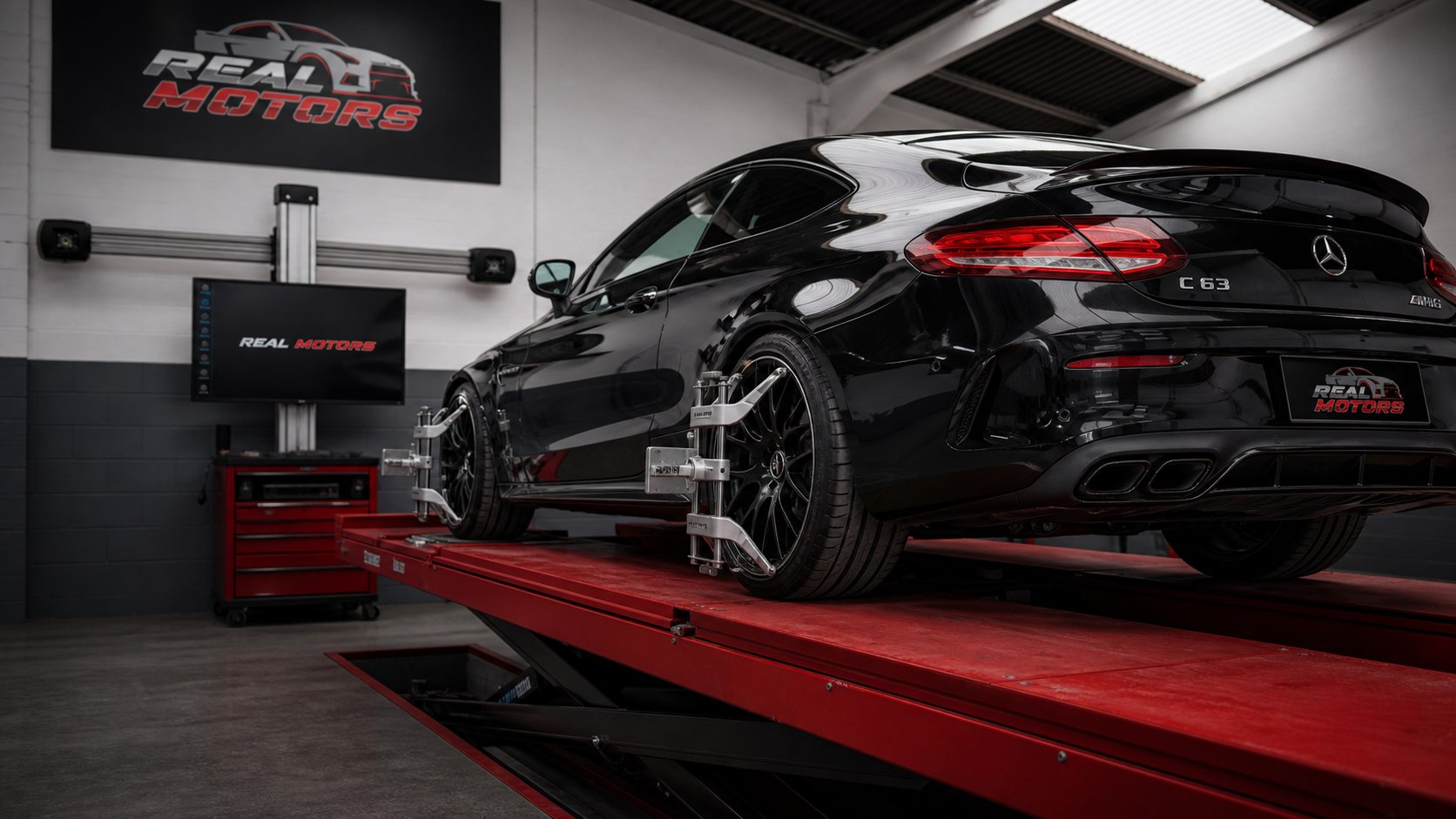 Mercedes C63 Coupe negro en alineado de precisión con garras en Real Motors